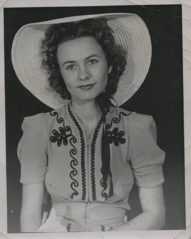 Untitled [Woman sits, wears embroidered shirt and round hat]