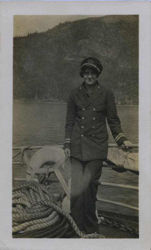 Untitled [Woman stands on ship, one hand on rail]