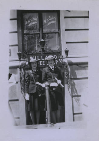 Untitled [Two women stand together, signs that read Round Robin and Willard Coffee Shop in the background]