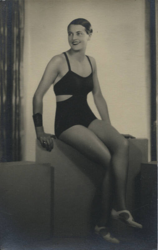 Untitled [Woman sits on crate, looks away, crosses legs]