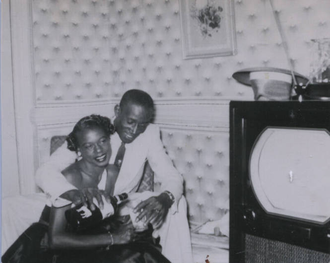 Untitled [Woman and man sit in living room, man pours drinks]