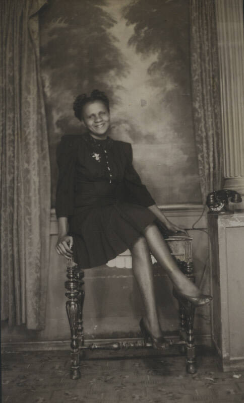 Untitled [Woman sits on table, crosses legs]