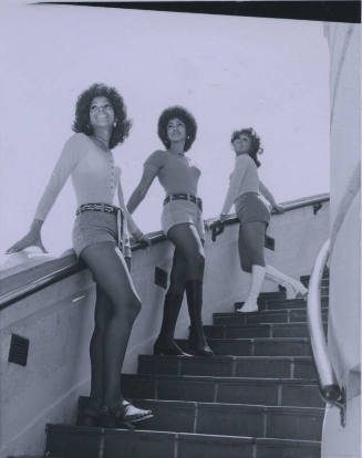 Untitled [Three women stand on stairs, hands on rails]