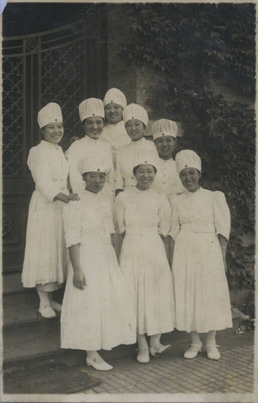 Untitled [Eight women stand on steps, wear matching attire]