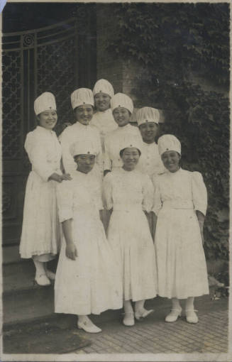 Untitled [Eight women stand on steps, wear matching attire]