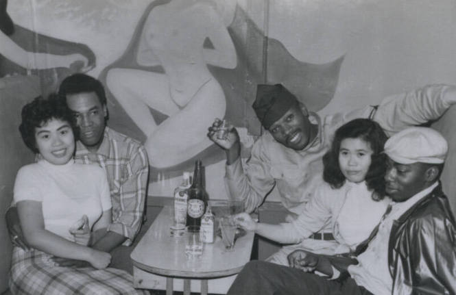 Untitled [Two women and three men sit in booth, drinks on table]
