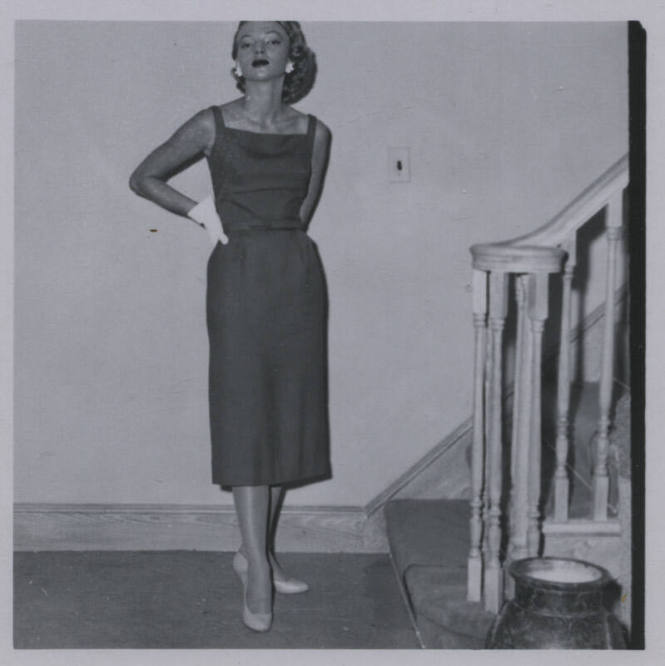 Untitled [Woman stands beside staircase, hand on hip]