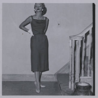 Untitled [Woman stands beside staircase, hand on hip]