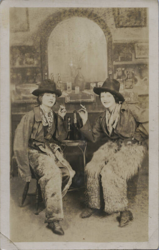 Untitled [Two women sit together, cigarettes in hand, bar in background]