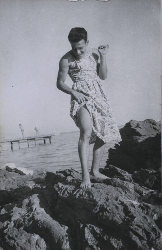 Untitled [Man stands on rock, looks down, body of water in background]