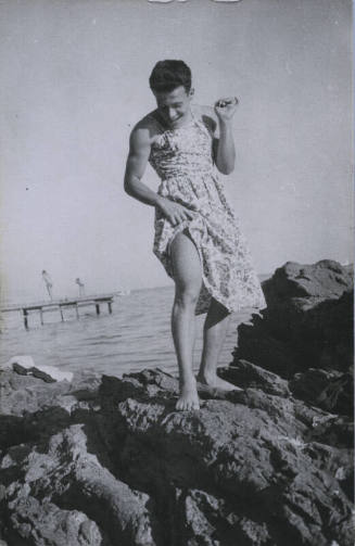 Untitled [Man stands on rock, looks down, body of water in background]