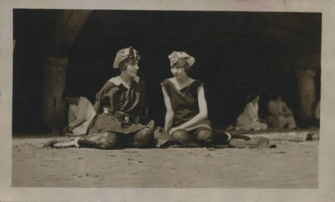 Untitled [Two women sit on field, legs to one side]