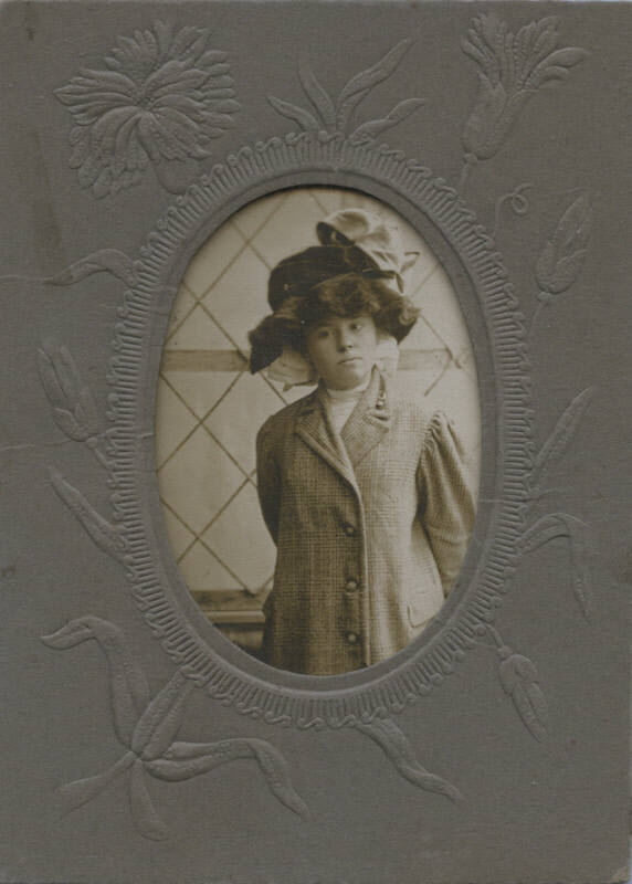 Untitled [Woman stands, hand behind her back, wears hat and coat]