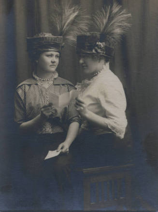 Untitled [Two women stand side by side, hold up pieces of paper]