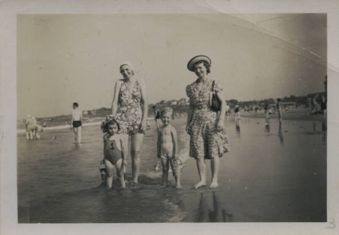 Untitled [Two women and two children stand on bench]