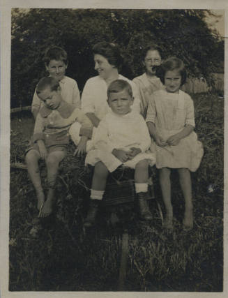 Untitled [Woman sits on haystack, five children by her sides]