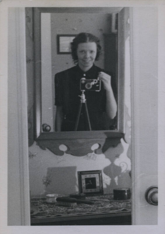 Untitled [Woman takes photograph of self in dresser mirror]