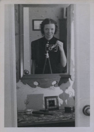 Untitled [Woman takes photograph of self in dresser mirror]