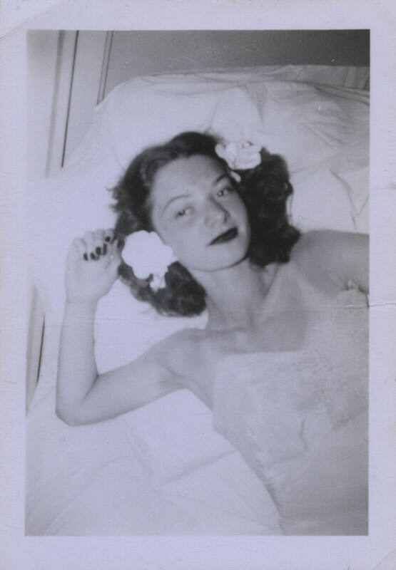 Untitled [Woman lays on bed, flowers in her hair]