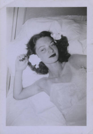 Untitled [Woman lays on bed, flowers in her hair]