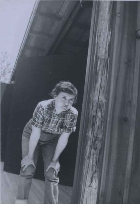 Untitled [Woman stands outside, hands on knees]