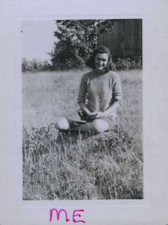 Untitled [Woman sits on field, legs to one side]