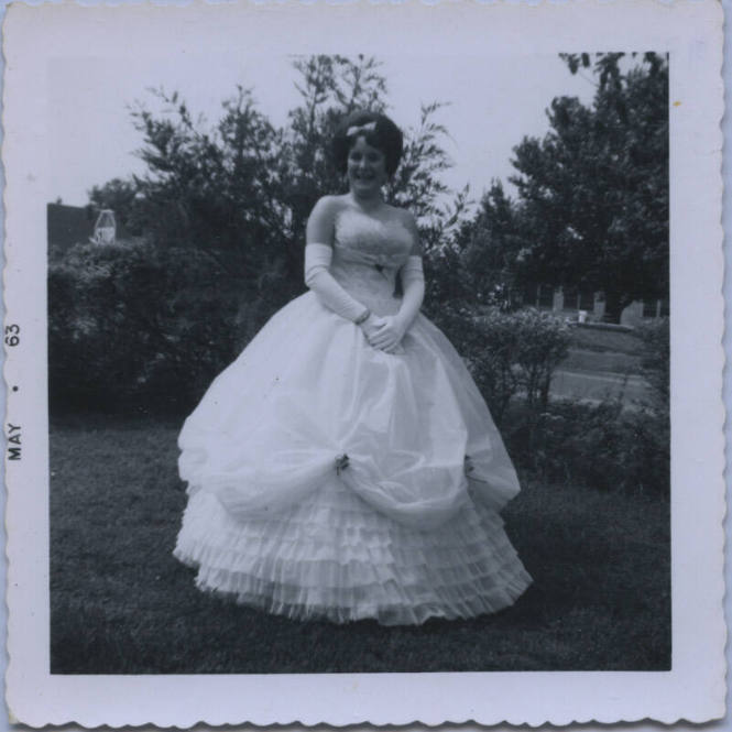 Untitled [Woman stands in garden, wears gown and gloves]