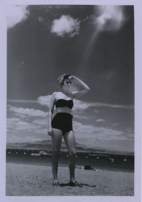 Untitled [Woman stands on beach, holds hand above eyes]