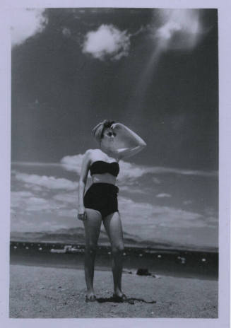 Untitled [Woman stands on beach, holds hand above eyes]
