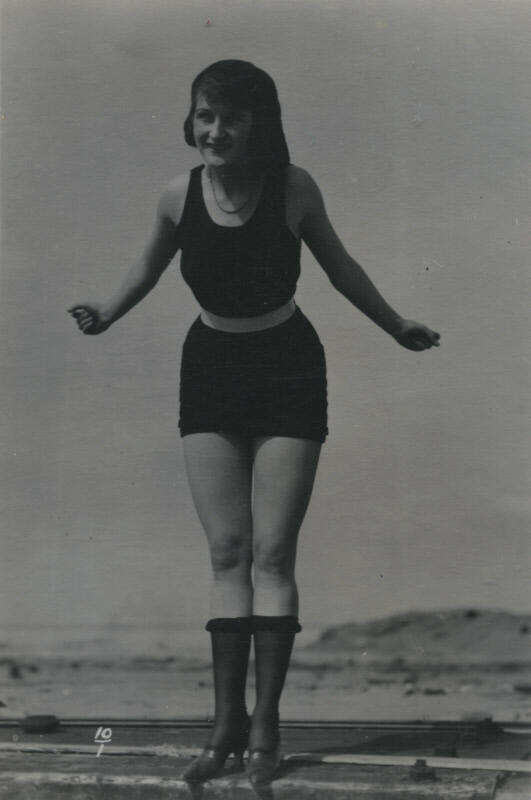 Untitled [Woman stands on ledge, hills in background]