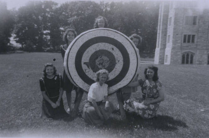 Untitled [Three women stand behind target, three kneel in front of it]