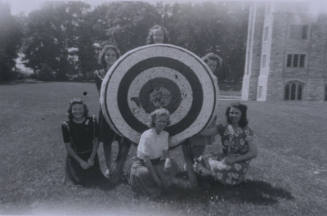 Untitled [Three women stand behind target, three kneel in front of it]