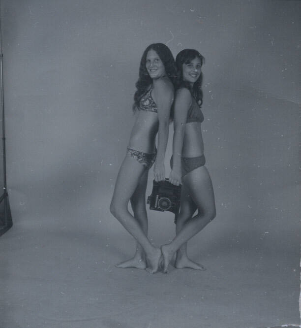 Untitled [Two women hold camera, stand back to back]