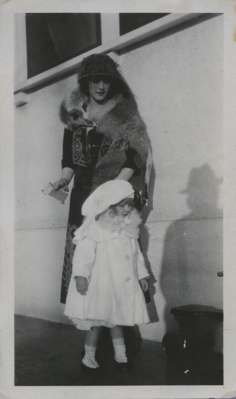 Untitled [Woman stands outside, child by her side]