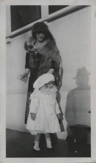 Untitled [Woman stands outside, child by her side]