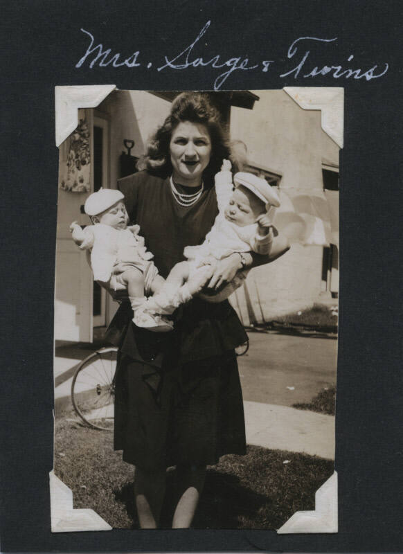 Untitled [Woman stands on lawn, carries twins on each arm]