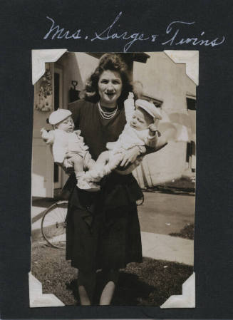Untitled [Woman stands on lawn, carries twins on each arm]