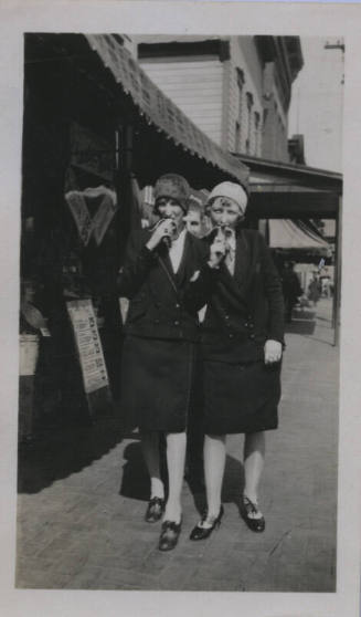 Untitled [Two women walk down street, eat bananas]