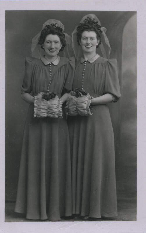Untitled [Two women stand side by side, wear matching outfits]