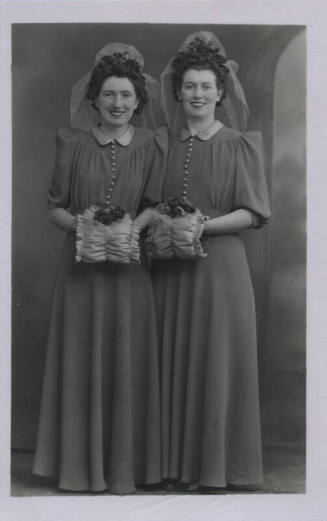 Untitled [Two women stand side by side, wear matching outfits]
