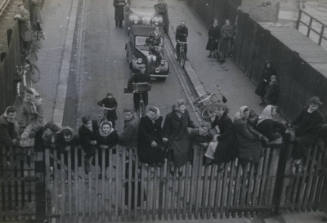 Untitled [Crowd sits atop fence]