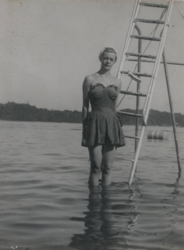 Untitled [Woman stands on ladder, submerged partially in body of water]