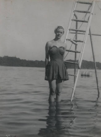 Untitled [Woman stands on ladder, submerged partially in body of water]