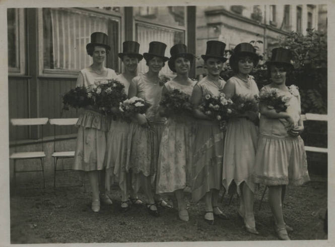 Untitled [Seven women stand in straight line, wear top hats]