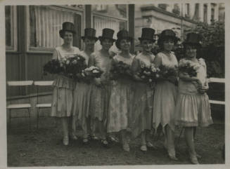 Untitled [Seven women stand in straight line, wear top hats]