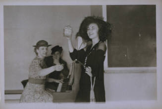 Untitled [Woman holds up bottole, one hand on hip]