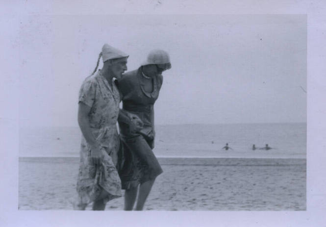 Untitled [Two people walk down beach hand in hand]