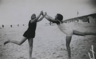 Untitled [Two women hold hands and stand on one leg in beach]
