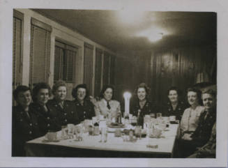 Untitled [Nine women sit around table, wear uniforms]