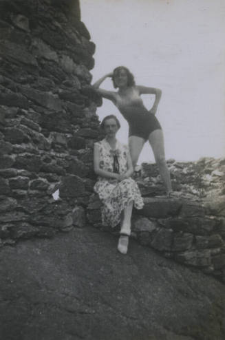 Untitled [Two women sit and stand on rock wall and ledge]
